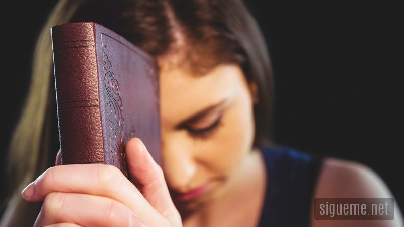 Joven leyendo la Biblia y orando a Dios