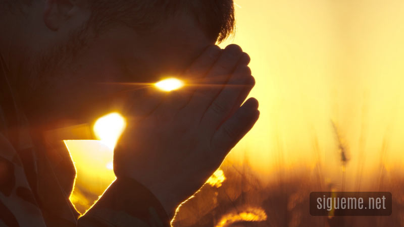 Hombre orando a Dios al amanecer