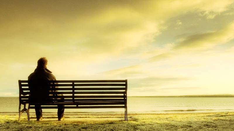 Hombre en soledad sentado frente al mar