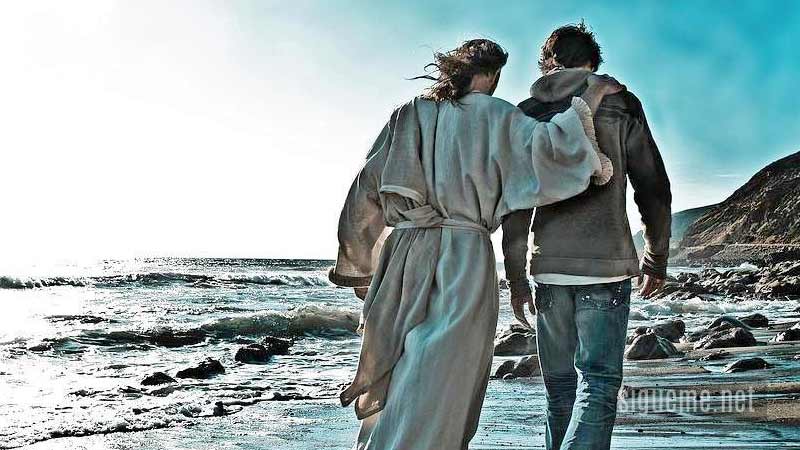 Joven camina con Jesús en amistad junto al mar