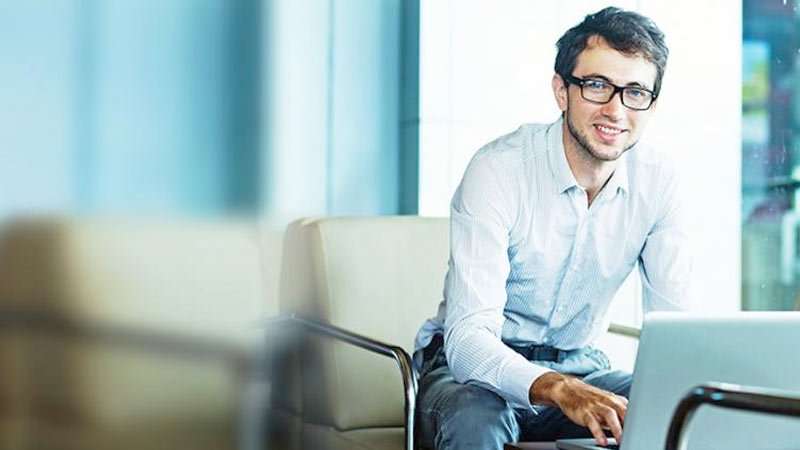 Joven empresario con laptop sonriendo