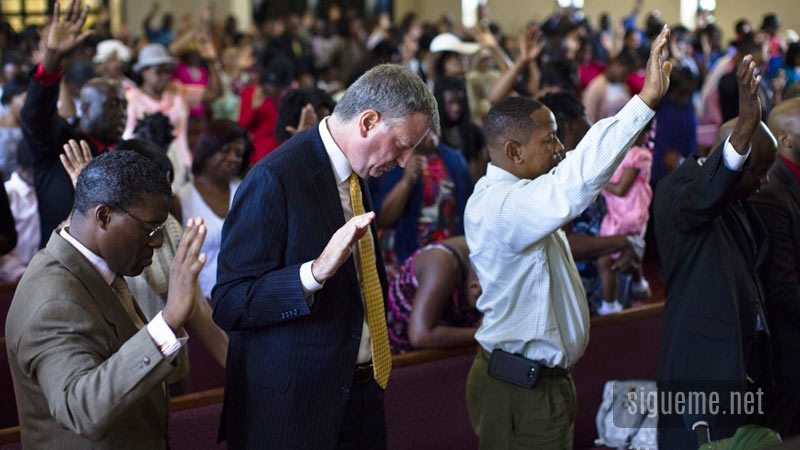 Ministros cristianos orando a Dios en la iglesia con manos levantadas
