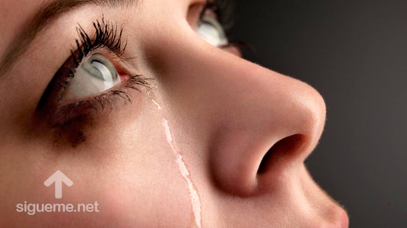 Mujer cristiana ora a Dios con lagrimas en los ojos