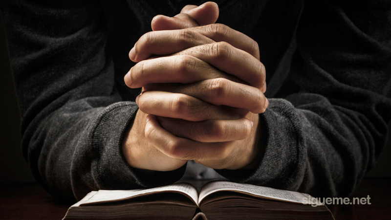 Hombre cristiano orando a Dios sobre su Biblia