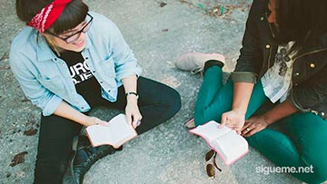 Jovenes cristianos leyendo la biblia sentados en el piso