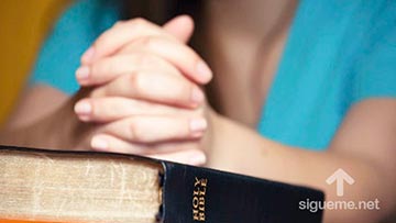 Mujer cristiana orando a Dios con la Biblia abierta
